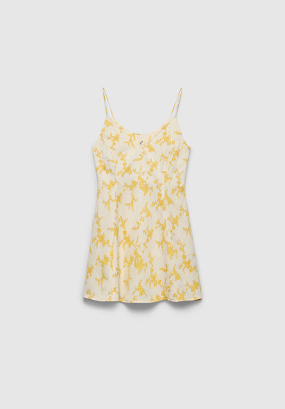 A cream-colored slip dress with thin spaghetti straps and a soft flared silhouette, featuring a delicate yellow floral print, displayed against a plain background.
