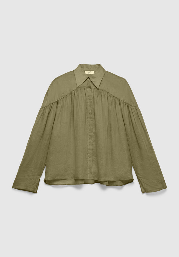 An olive green long-sleeve blouse with a pointed collar and concealed button placket, featuring gathered detailing across the chest and shoulders for a loose, flowy silhouette, displayed against a plain background.
