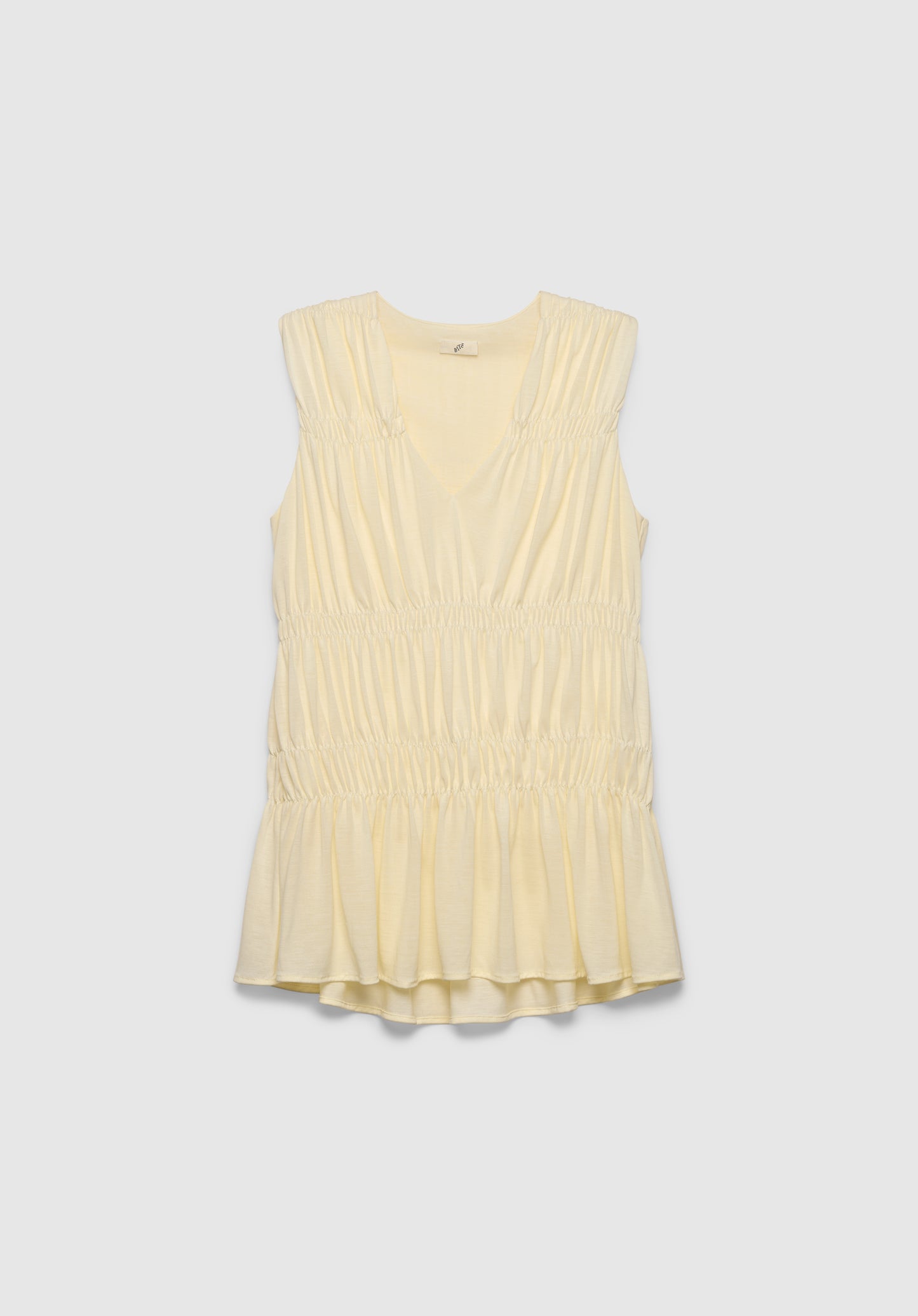 A light cream sleeveless top with a V-neckline, featuring gathered detailing at the shoulders and waist and a softly flared hem, displayed against a plain background.
