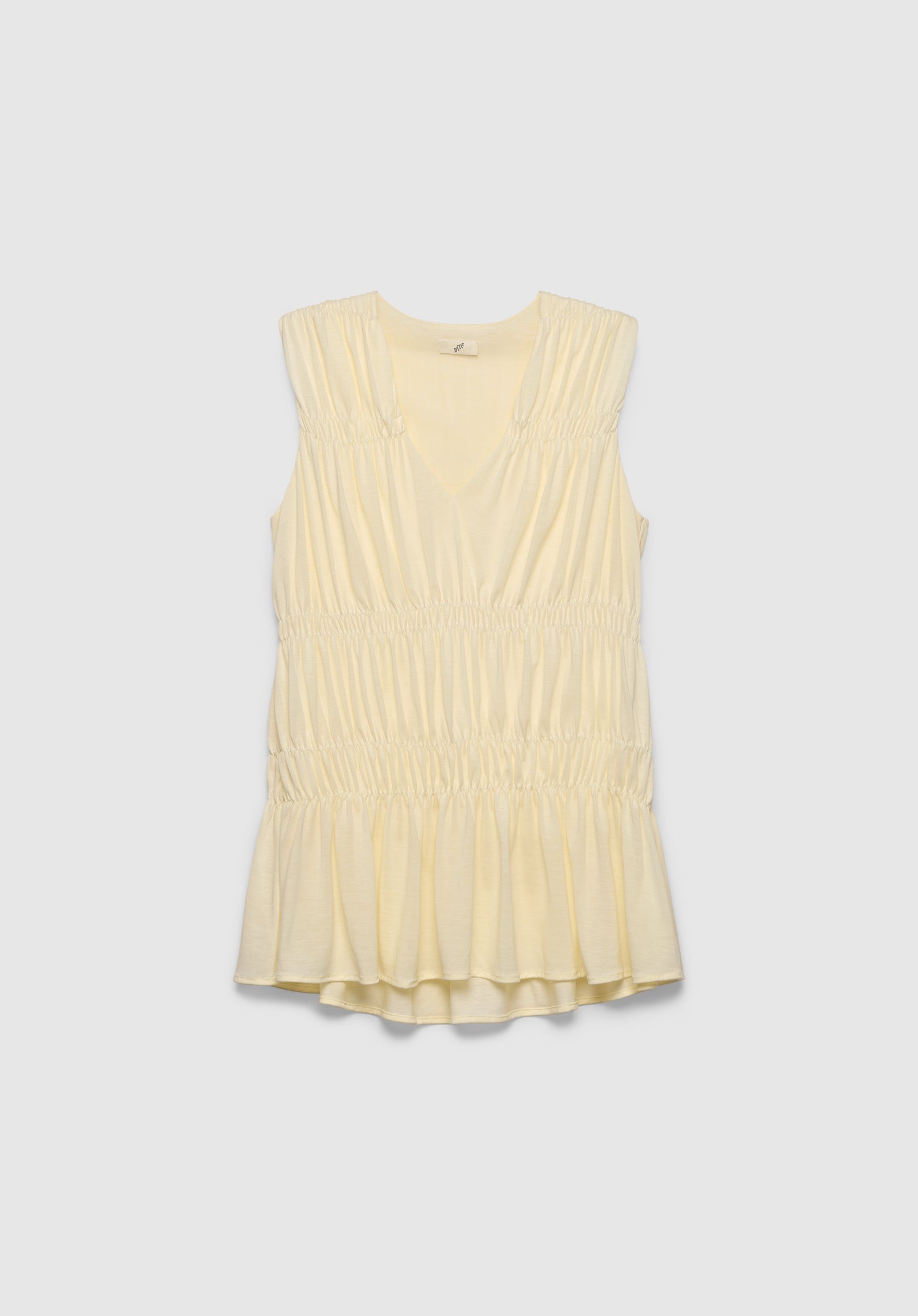 A light cream sleeveless top with a V-neckline, featuring gathered detailing at the shoulders and waist and a softly flared hem, displayed against a plain background.
