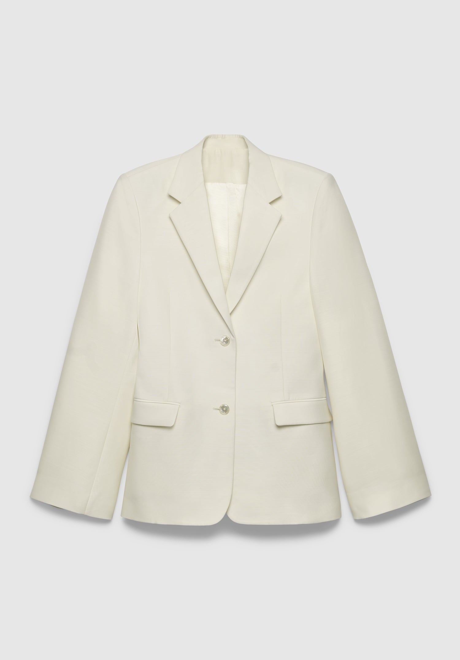 A cream-colored tailored blazer with a structured fit, featuring a notched lapel, two-button front closure, and flap pockets, displayed against a plain background.
