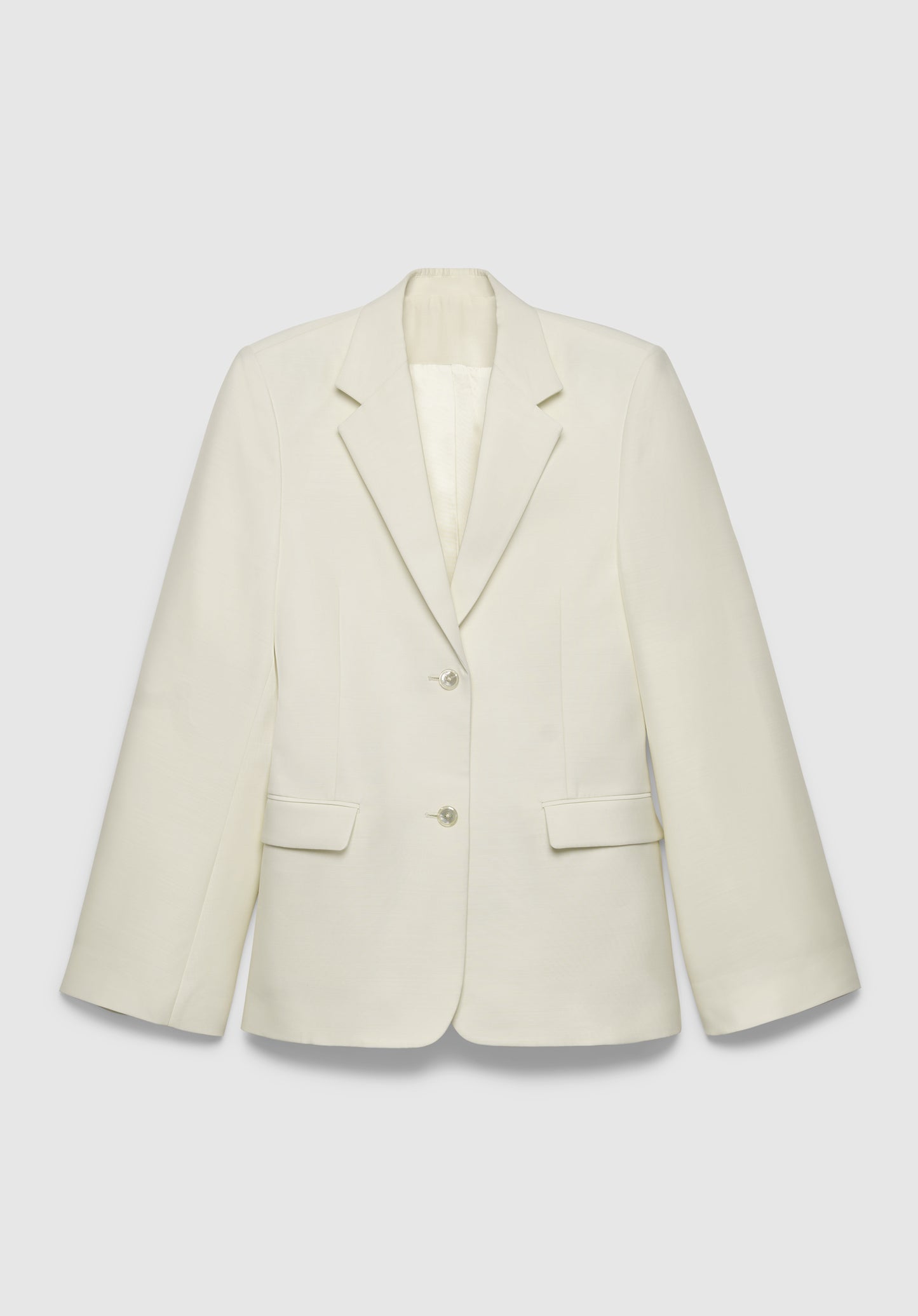 A cream-colored tailored blazer with a structured fit, featuring a notched lapel, two-button front closure, and flap pockets, displayed against a plain background.

